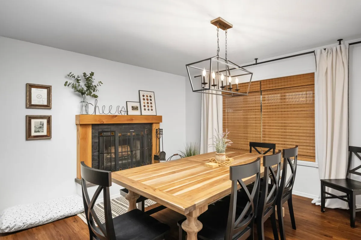 A cozy interior dining area featuring a table set near a fireplace, chandelier overhead, and tasteful wall art. The setting is intimate and warm, evoking the atmosphere of quiet dinners and meaningful conversation.
