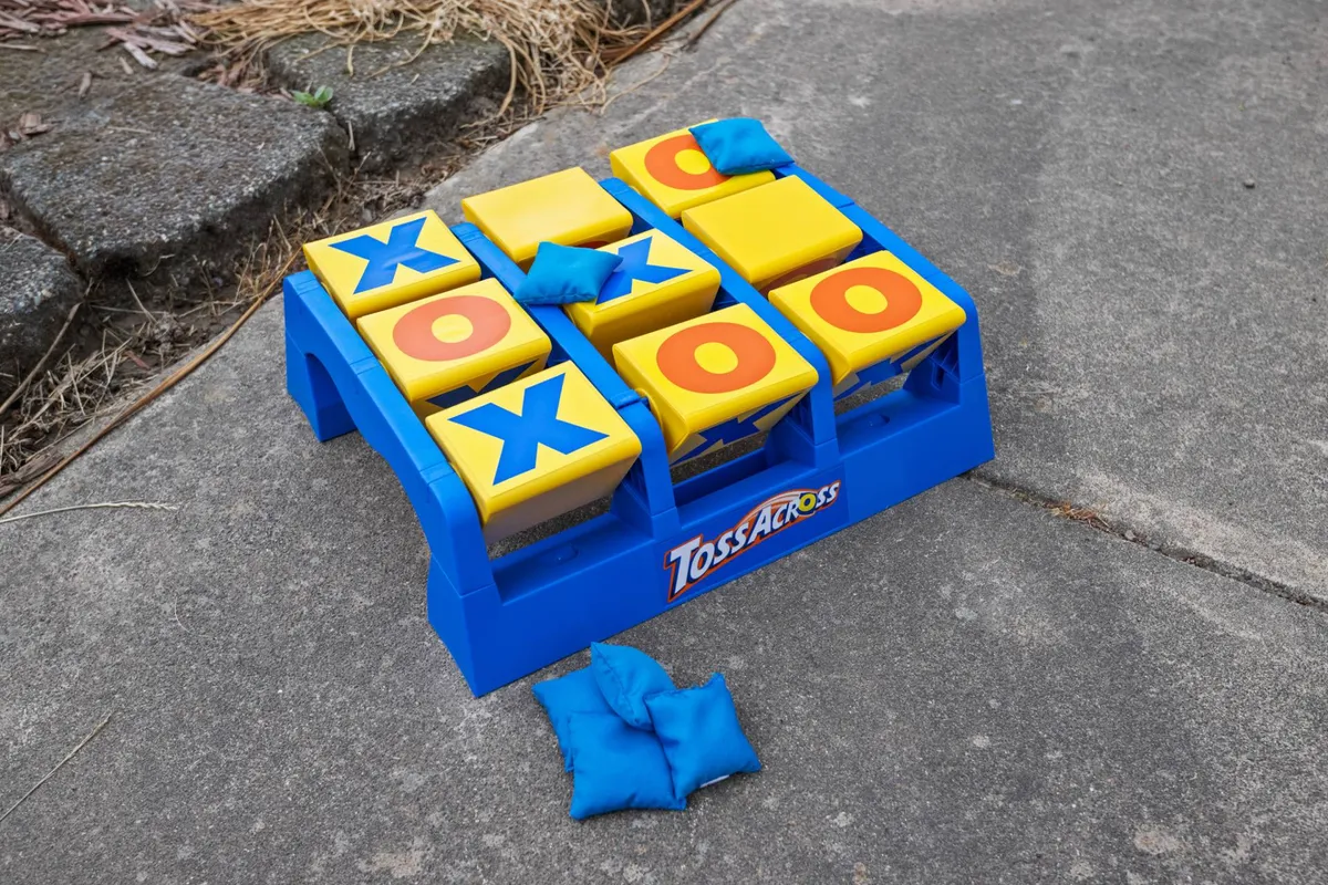 This image captures a Toss Across game board with bean bags set out on a green lawn, suggesting an inviting and playful backyard environment designed for family fun. The scene is bright and lively, emphasizing the potential for outdoor play and bonding.