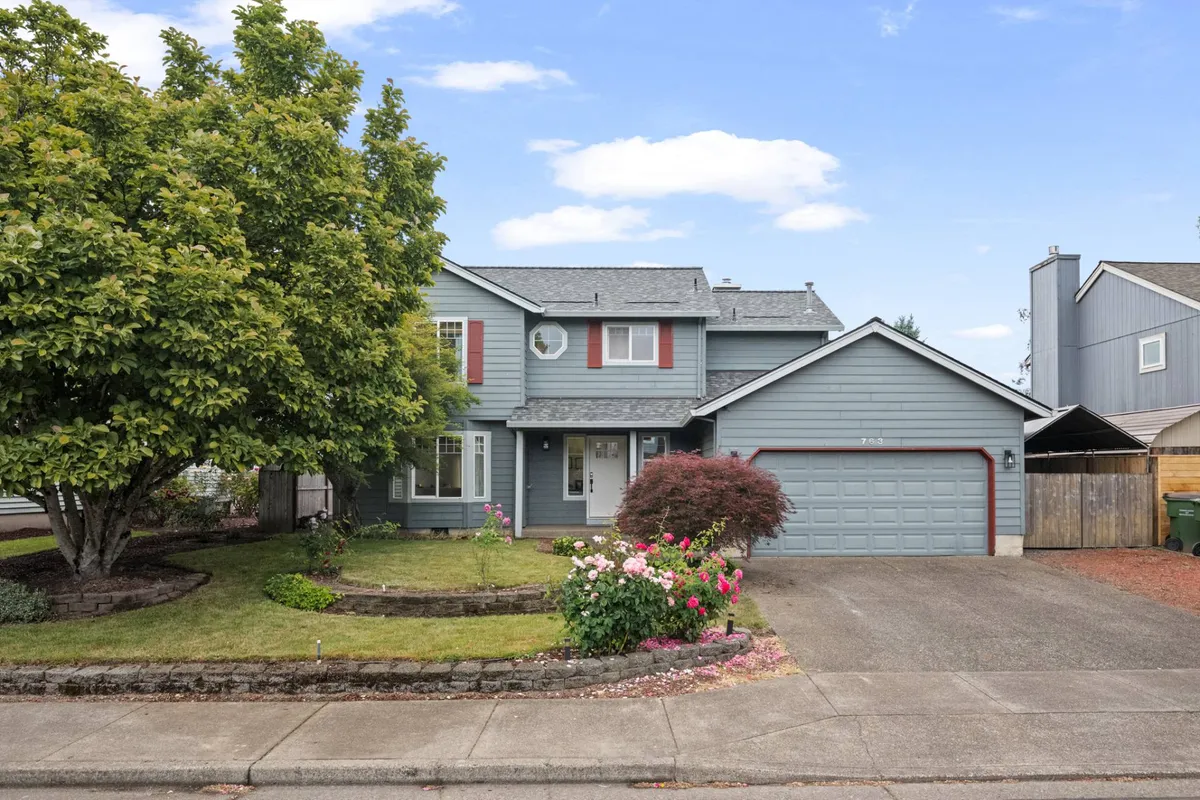 A two-story home with a lush, flower-filled front yard and a welcoming porch. The landscaping is vibrant, and the space hints at a safe, family-friendly setting perfect for gatherings and outdoor play.
