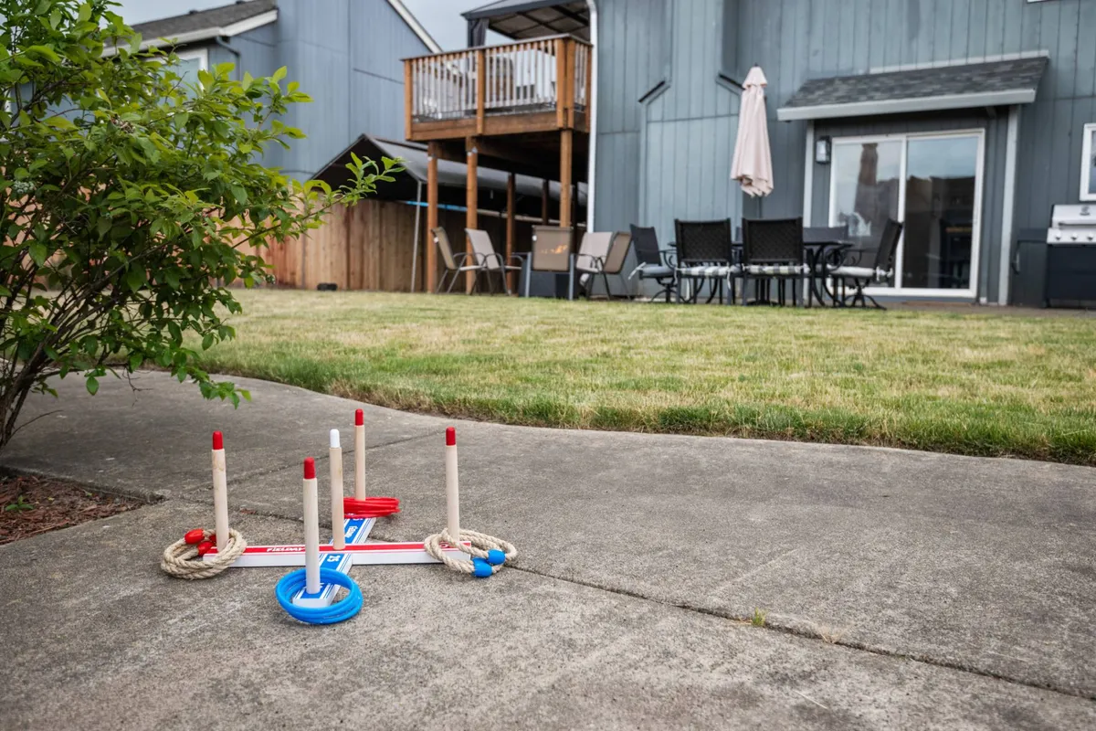 This exterior image features a backyard deck outfitted with patio furniture and a ring toss game set up, suggesting a casual and inviting space for outdoor activities. The scene hints at opportunities for family gatherings, relaxed afternoons, and friendly competition.