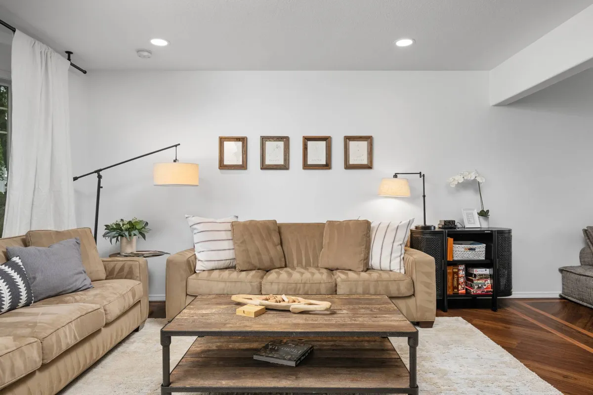A comfortable living area with a plush sofa, coffee table, floor lamp, side table, and wall art. The arrangement encourages relaxation, conversation, and shared entertainment, embodying the warm, welcoming ambiance described.