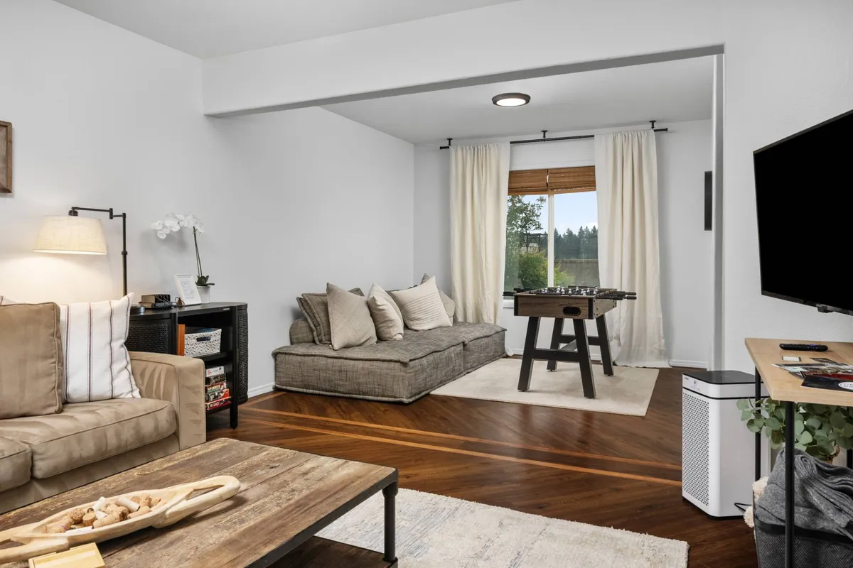 A comfortable living area with a sofa, coffee table, game table, and a window view. The arrangement suggests opportunities for families and friends to relax, play games, or unwind together in a peaceful setting.